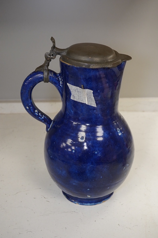 An 18th century German blue glazed faience jug with pewter lid, 30cm. Condition - poor to fair